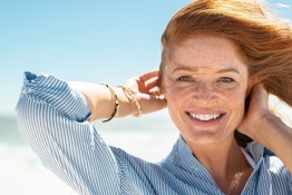 junge rothaarige Frau lächelt mit wehenden Haaren