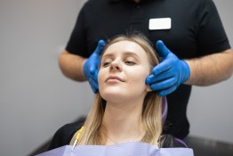 Zahnarzt tastet Kiefer einer Patientin ab