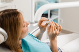 Junge Patientin hält Zahnschiene in der Hand